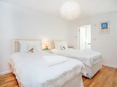 two beds in a room with white sheets at Lookout in Downderry