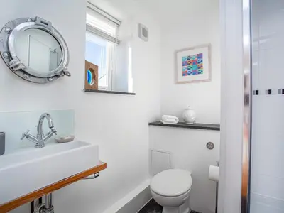 a white bathroom with a toilet and a mirror at Lookout in Downderry