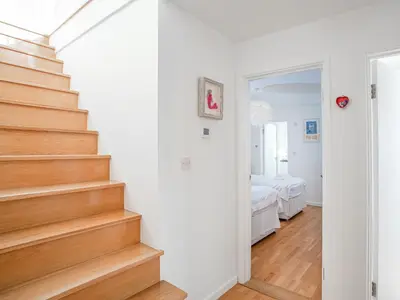 a white room with a staircase and a bedroom at Lookout in Downderry