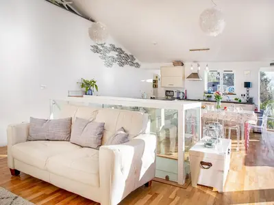 a living room with a white couch and a kitchen at Lookout in Downderry