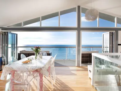 a dining room with a table and a view of the ocean at Lookout in Downderry