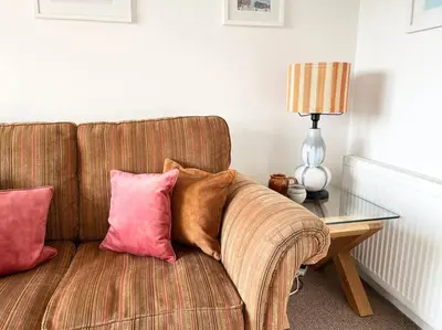 a couch with pillows on it next to a table at Seascape Stay No 4, Sea View & Parking in Falmouth
