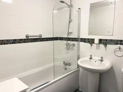 a white bathroom with a sink and a shower at Seascape Stay No 4, Sea View & Parking in Falmouth