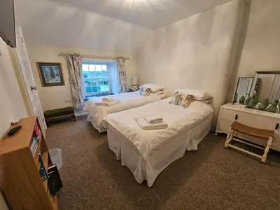 a bedroom with two beds and a window at End Cottage Veryan Cornwall in Truro