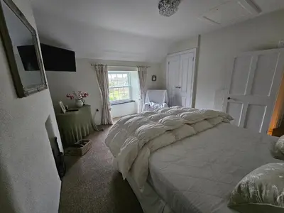 a bedroom with a large bed and a window at End Cottage Veryan Cornwall in Truro