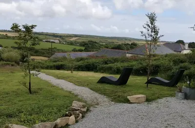 two black chairs sitting in the grass near a path at The Daffodil Hut in Porkellis