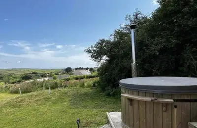 a hot tub sitting on top of a field at The Daffodil Hut in Porkellis