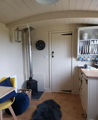 a room with a kitchen with a stove and a door at The Daffodil Hut in Porkellis