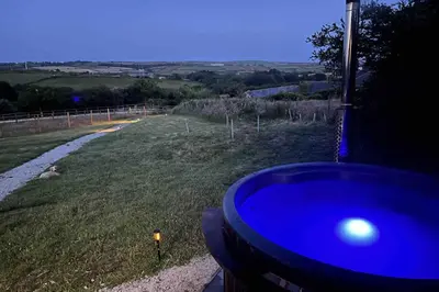 a blue bath tub in a field with a road at The Daffodil Hut in Porkellis