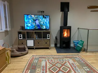 a living room with a flat screen tv and a fireplace at Lovely flat, balcony & woodstove, parking close in St. Agnes