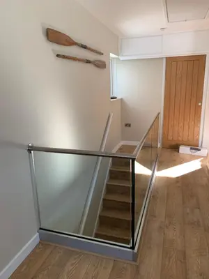 a staircase in a room with a glass railing at Lovely flat, balcony & woodstove, parking close in St. Agnes