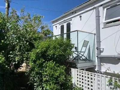 a balcony with a chair on the side of a house at Lovely flat, balcony & woodstove, parking close in St. Agnes