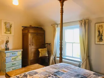 a bedroom with a bed and a dresser and a window at Exceptional retreat near Cornwall Coast in Tywardreath