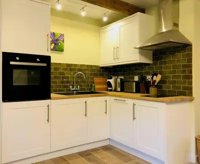 a kitchen with white cabinets and a black appliance at Exceptional retreat near Cornwall Coast in Tywardreath