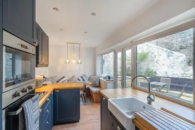 a kitchen with a sink and a large window at Charming Cornish Cottage in the heart of St Agnes in St. Agnes