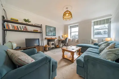 a living room with two blue couches and a tv at Charming Cornish Cottage in the heart of St Agnes in St. Agnes