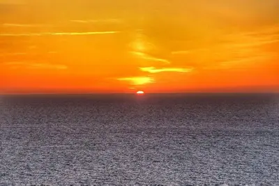 a sunset over the ocean with the sun in the sky at Charming Cornish Cottage in the heart of St Agnes in St. Agnes