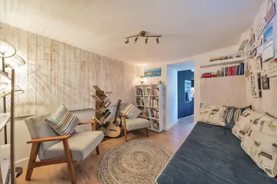 a living room with a couch and chairs and a book shelf at Charming Cornish Cottage in the heart of St Agnes in St. Agnes