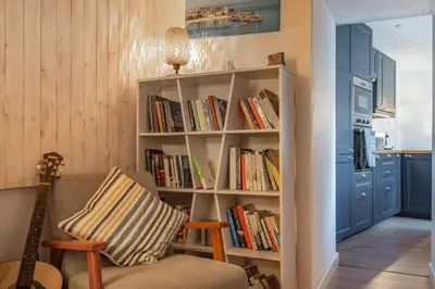a living room with a book shelf filled with books at Charming Cornish Cottage in the heart of St Agnes in St. Agnes