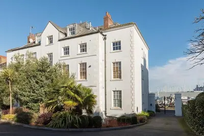 a large white house with trees in front of it at Stone's Throw - 2 Bed Apartment Centre of Falmouth in Falmouth