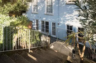 a white fence in front of a blue house at Stone's Throw - 2 Bed Apartment Centre of Falmouth in Falmouth