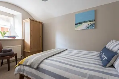 a bedroom with a blue and white bed and a window at Stone's Throw - 2 Bed Apartment Centre of Falmouth in Falmouth