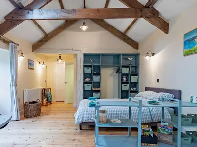 a bedroom with a blue bed and a book shelf at Tiptoe Barn in Liskeard