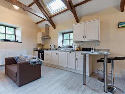 a kitchen with white cabinets and a table at Tiptoe Barn in Liskeard