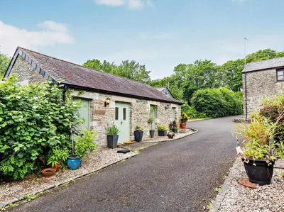 a cottage with potted plants on the side of the road at Tiptoe Barn in Liskeard