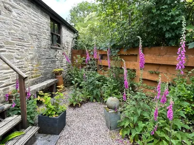 a garden with purple flowers next to a building at Tiptoe Barn in Liskeard
