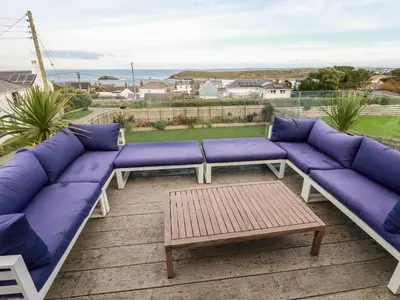 a patio with purple couches and a coffee table at Sea View House in Newquay