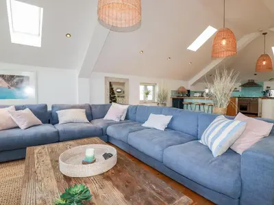 a living room with a blue couch and a table at Sea View House in Newquay