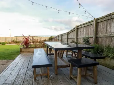 a table and benches on a deck with a fence at Sea View House in Newquay