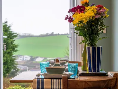 a table with a vase of flowers and wine glasses at Holiday Home Valley View by Interhome in Mevagissey