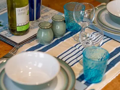a table with plates and glasses and a wine bottle at Holiday Home Valley View by Interhome in Mevagissey