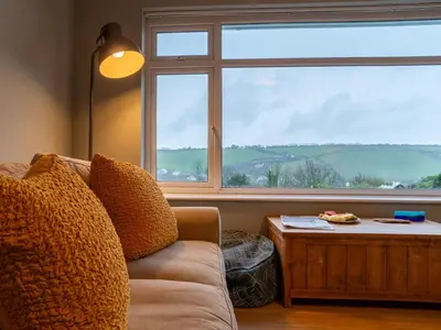 a living room with a couch and a large window at Holiday Home Valley View by Interhome in Mevagissey