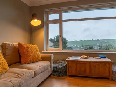 a living room with a couch and a large window at Holiday Home Valley View by Interhome in Mevagissey