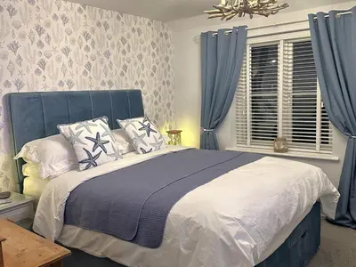 a bedroom with a large bed with blue curtains at 3 Bed in Newquay oc-47630 in Newquay