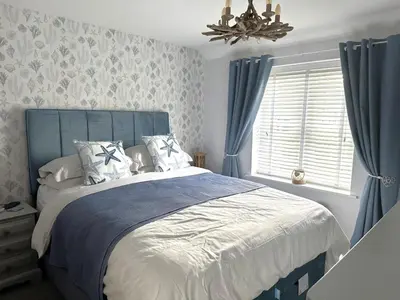 a bedroom with a bed with blue curtains and a chandelier at 3 Bed in Newquay oc-47630 in Newquay