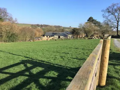 a fence in a field with a house in the background at 4 Bed in Callington oc-54343 in Linkinhorne