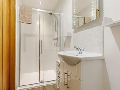 a white bathroom with a shower and a sink at 1 Bed in Callington oc-54344 in Linkinhorne