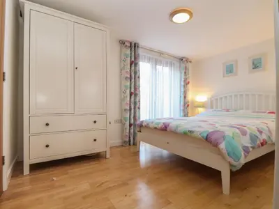 a bedroom with a bed and a dresser and a window at Little Fernleigh in Helston