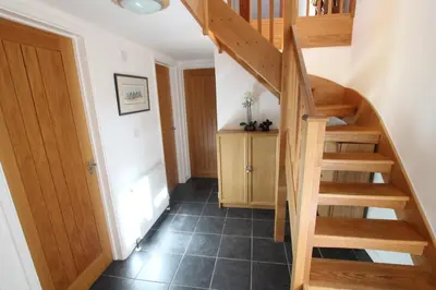 a hallway with a wooden staircase and a stair case at Little Fernleigh in Helston