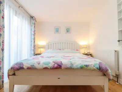 a bedroom with a white bed with a colorful comforter at Little Fernleigh in Helston