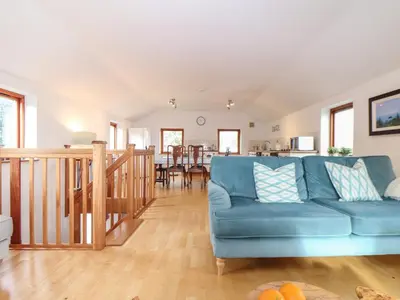 a living room with a blue couch and a kitchen at Little Fernleigh in Helston