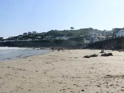 a beach with people walking on the sand and houses at Little Fernleigh in Helston