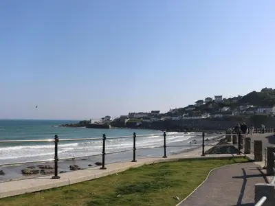a beach with people walking on the sand and the ocean at Little Fernleigh in Helston