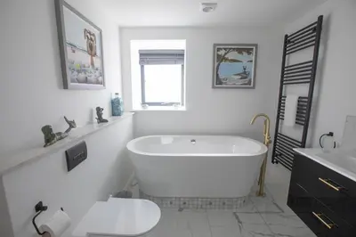 a white bathroom with a tub and a sink at UPPER BEACH HOUSE in Portreath