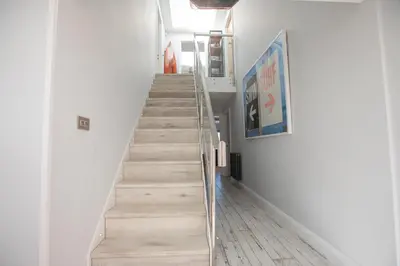 a staircase in a hallway with white walls and wooden floors at UPPER BEACH HOUSE in Portreath