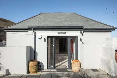 a white house with a door and a fence at UPPER BEACH HOUSE in Portreath